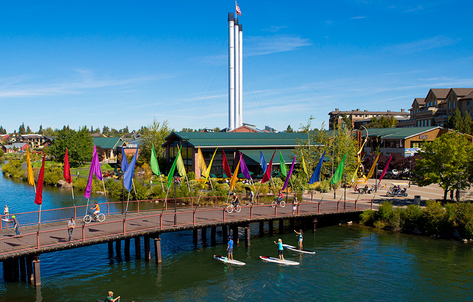 Paddleboarders on the Deschutes River beside the Old Mill District footbridge in Bend
